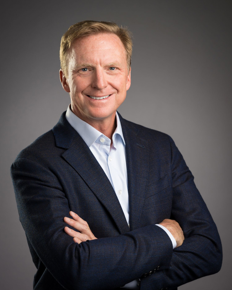 Dr. Jared Anderson, dentist and practice owner, smiling confidently in a navy blazer with arms crossed