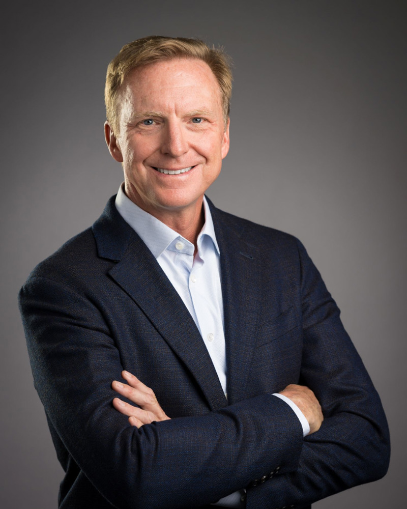 Dr. Jared Anderson, dentist and practice owner, smiling confidently in a navy blazer with arms crossed