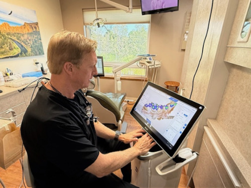 Dentist reviewing a 3D digital impression of teeth on a touchscreen scanner display chairside
