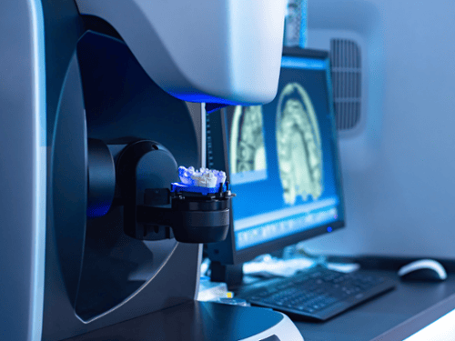 CEREC milling machine crafting a same-day dental crown with 3D imaging on monitor