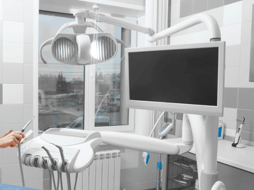 Ceiling-mounted TV monitor and dental treatment light in a modern dental operatory